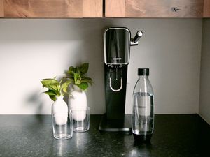 黑色SodaStream与两个眼镜和一个厨房工作台面SodaStream瓶子旁边