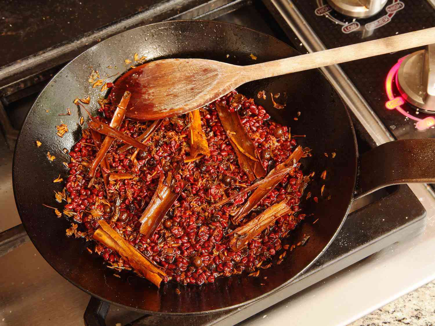 Toasting spices and cinnamon sticks in a skillet.