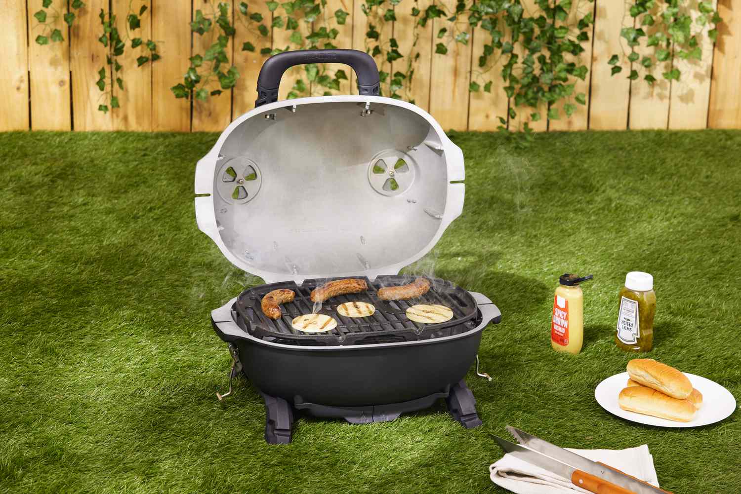 便携式木炭烧烤煮香肠,驻扎在一个草坪