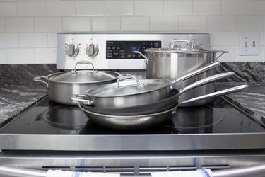 Cookware on a glass stovetop, including a stainless steel skillet, nonstick skillet, saute pan, rondeau, and stockpot.
