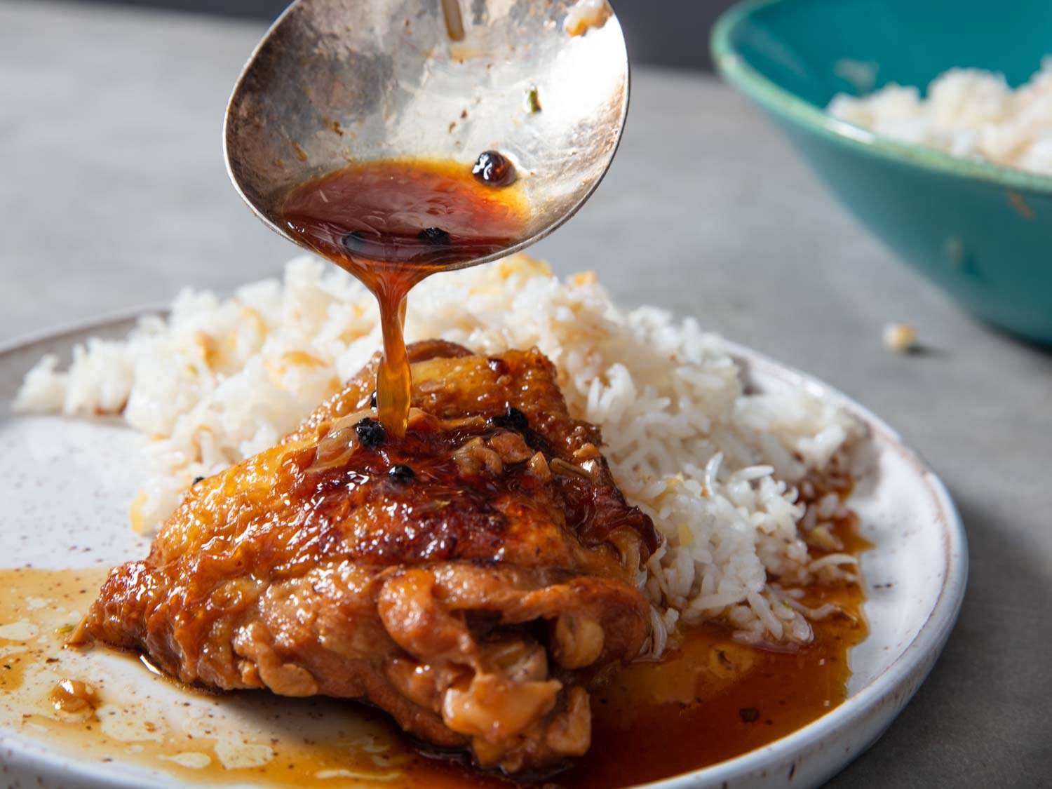 用白米饭盛一盘阿杜波鸡，用勺子把更多的阿杜波酱淋在鸡腿上
