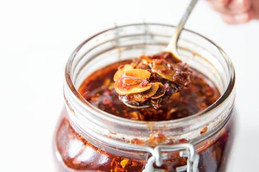 Homemade spicy chili crisp being spooned out of a jar