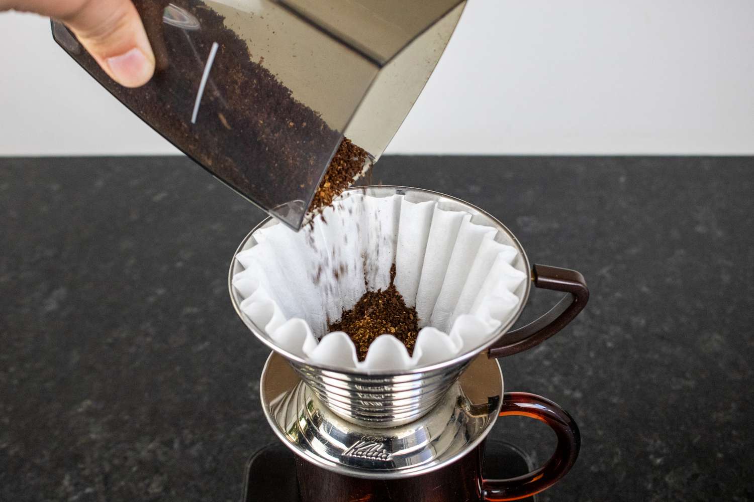 一只手把咖啡粉倒进咖啡机的滤网