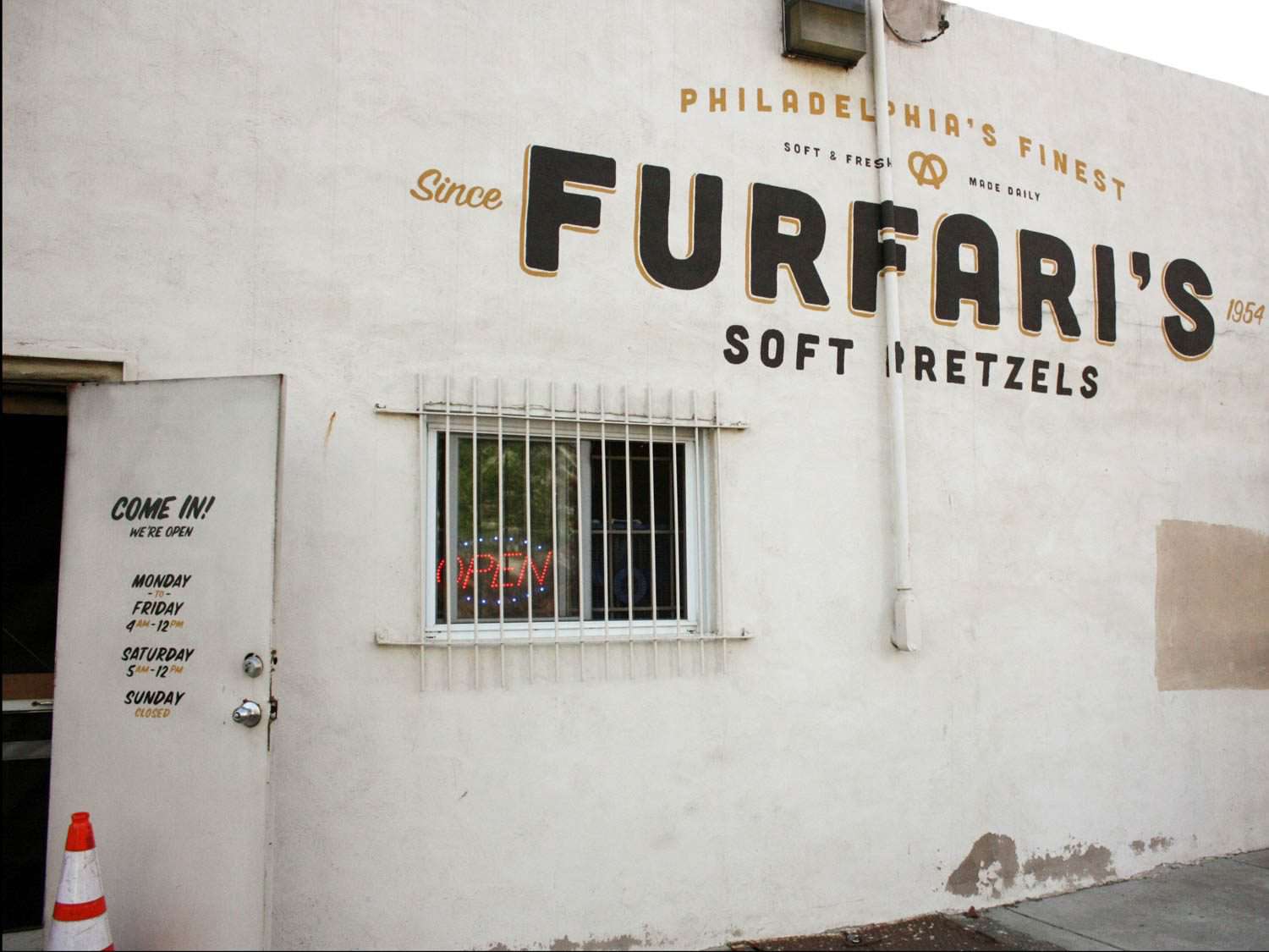 费城一家名为Furfari’s Soft Pretzels的椒盐饼干面包店的白色外观，敞开的门和霓虹灯