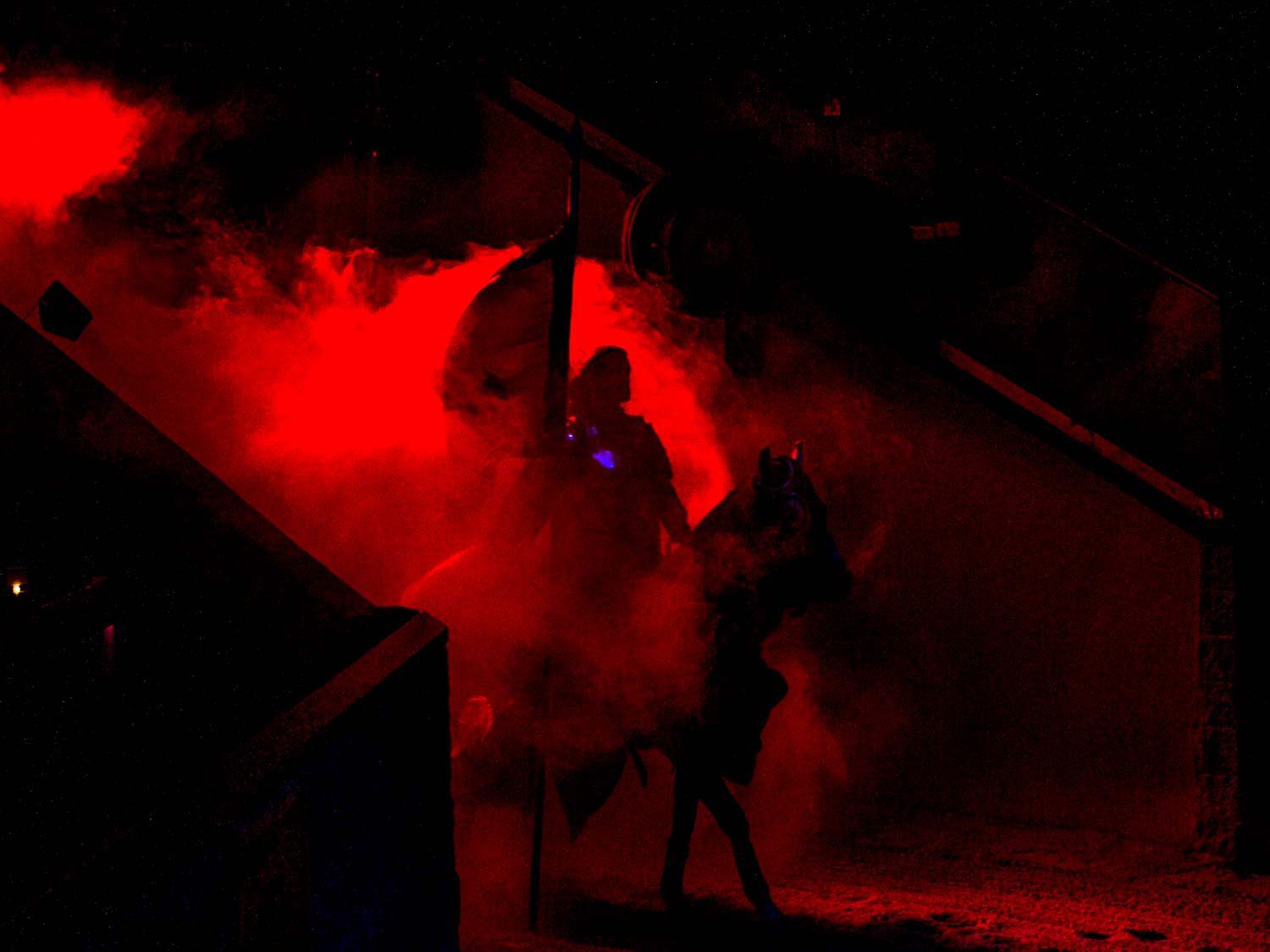 中世纪骑士骑在马背上的骑士在烟雾和红光中进入竞技场