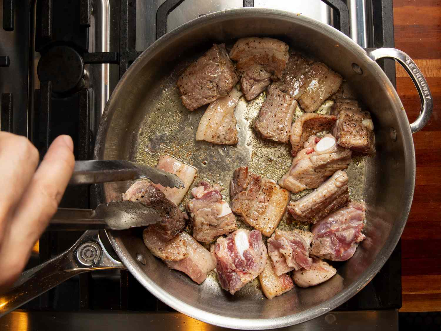 Overhead view of browning pork in pot