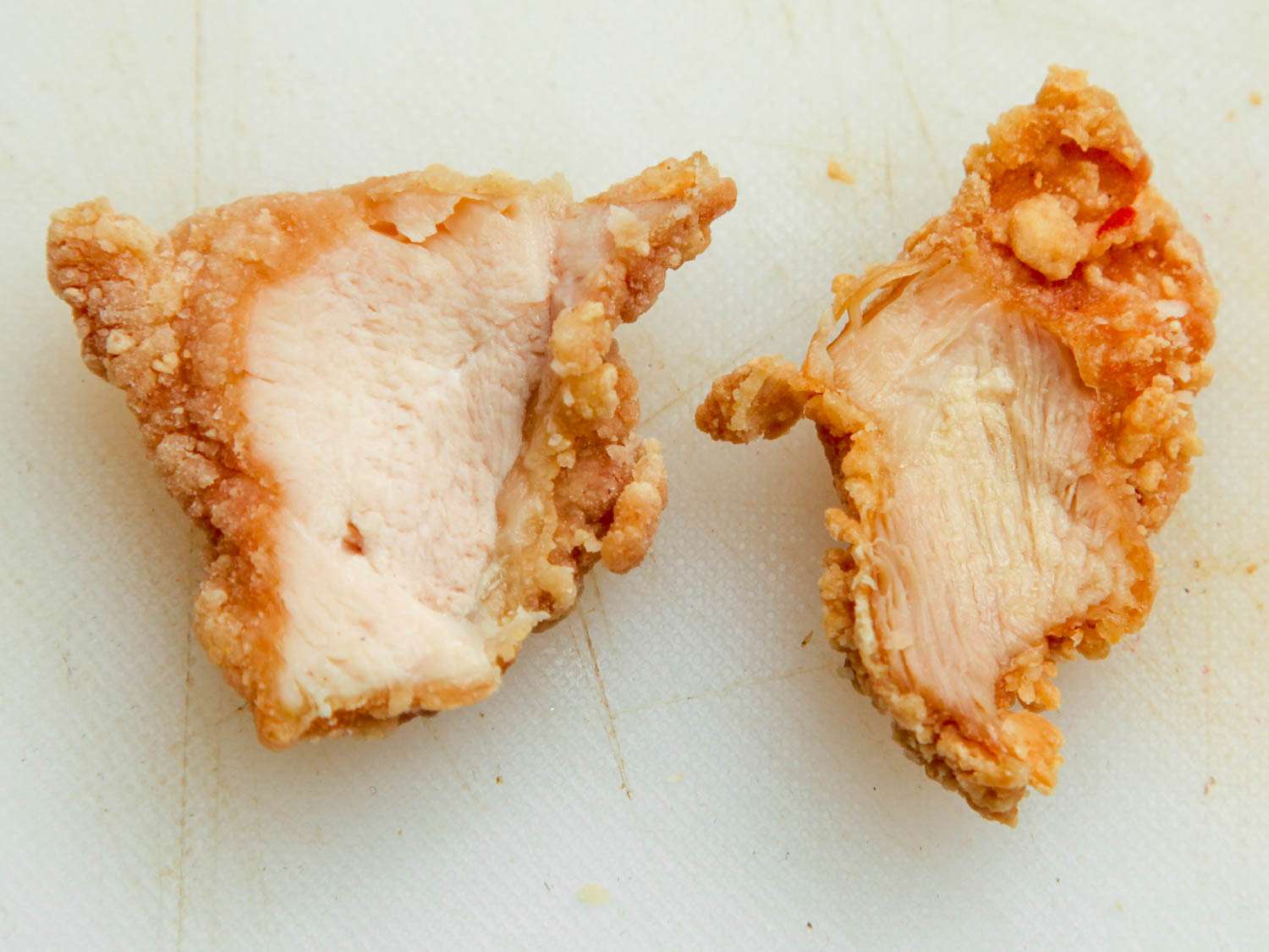 炸鸡胸肉(左)和炸鸡腿肉(右)并排放在白色砧板上。gydF4y2Ba