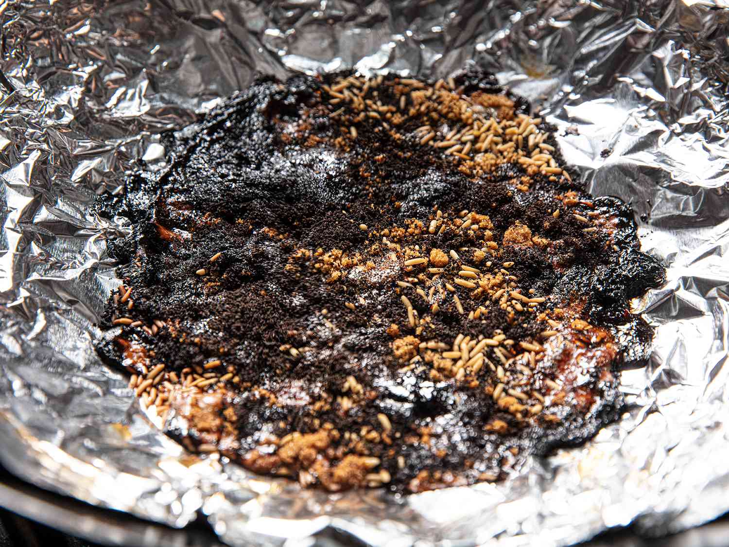 在锡箔内衬的锅中，部分燃烧的冒烟材料的近景。