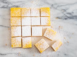 开销图像显示切片柠檬酒吧方格加上糖粉在大理石工作台面。