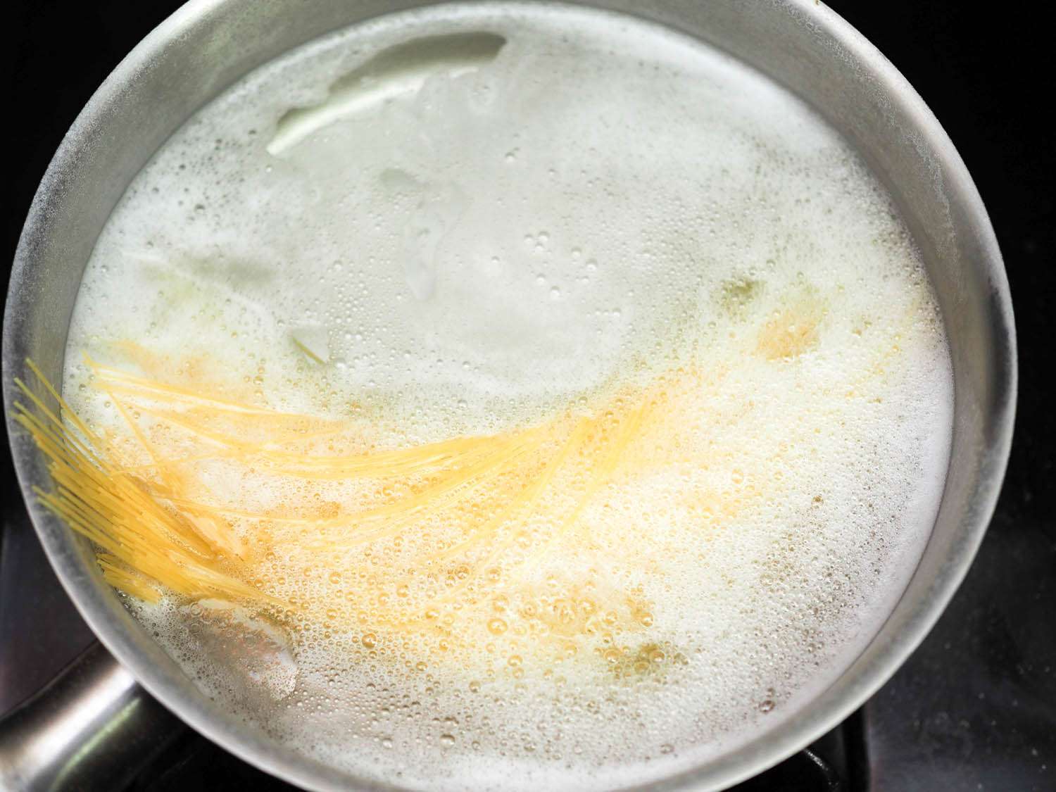 将干的天使毛意面加入一锅沸水中，加入盐和小苏打。