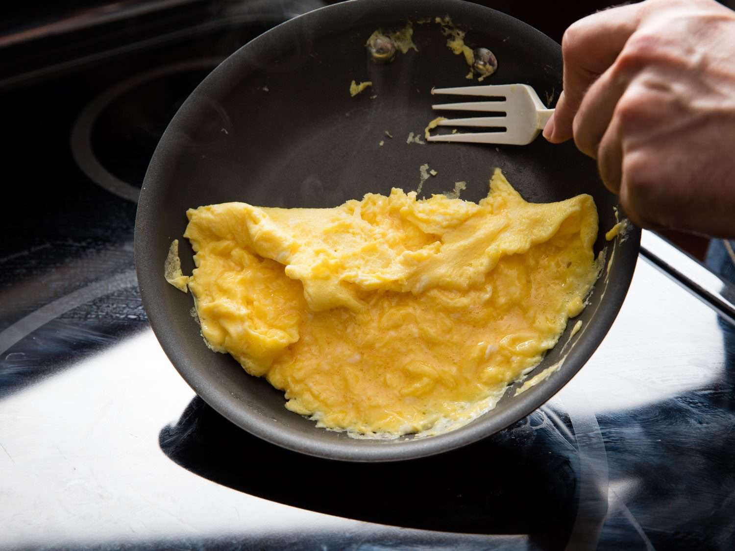 用塑料叉子把大块的炒鸡蛋凝块刮向不粘锅的中心
