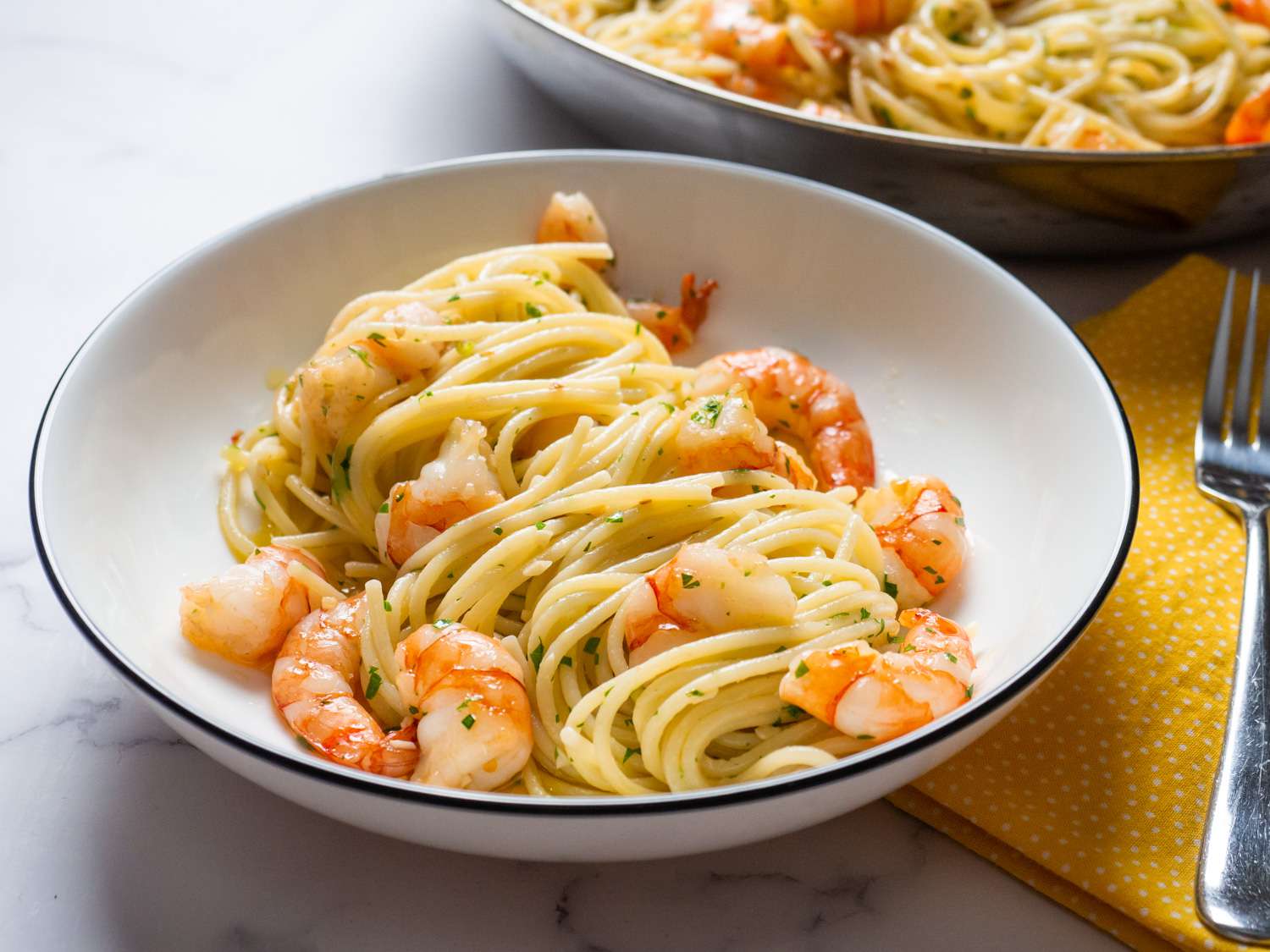 A bowl of shrimp scampi with pasta.
