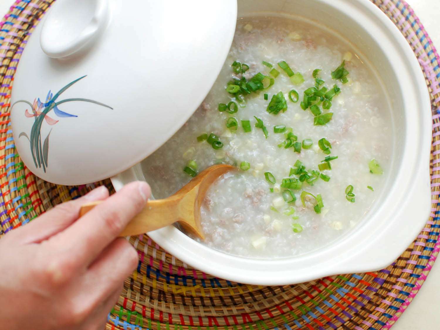 Stirring finished congee with a wooden spoon.