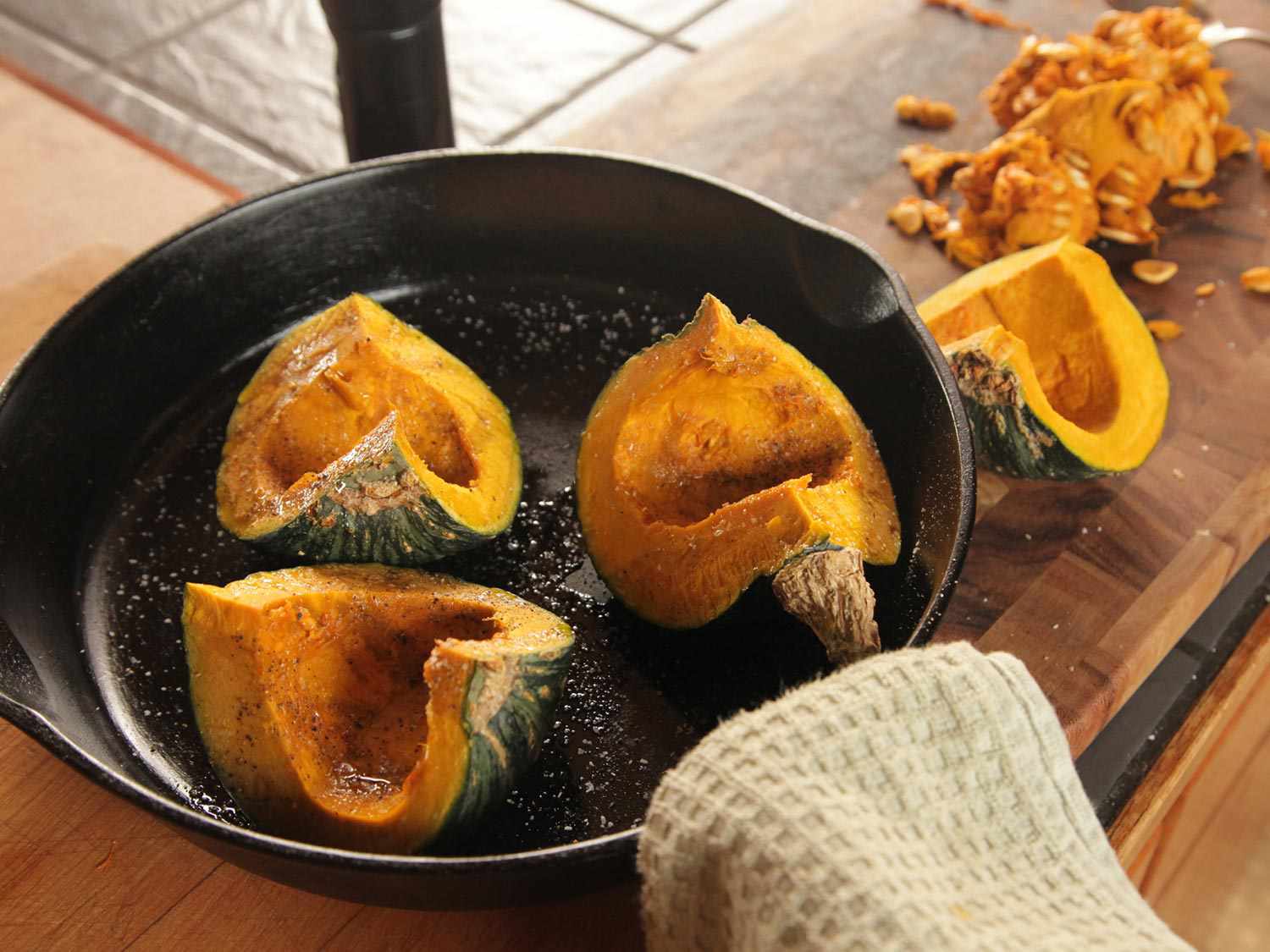 在铸铁煎锅中放入三块调味的、去籽的南瓜，切成四等份，准备烤。(第四节种子被搁置一旁。)