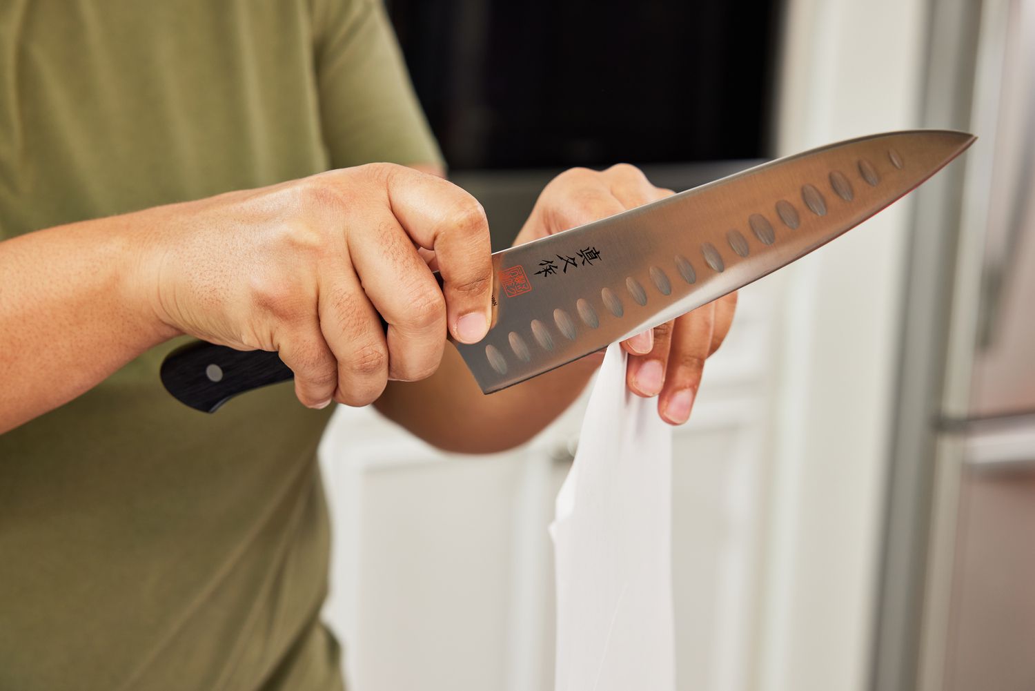 一只手拿着一把日式厨师刀，用它切开一张打印纸