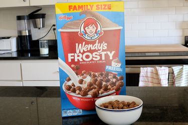 A box of Wendy's Frosty Cereal (and a bowl of the cereal) atop a black counter.