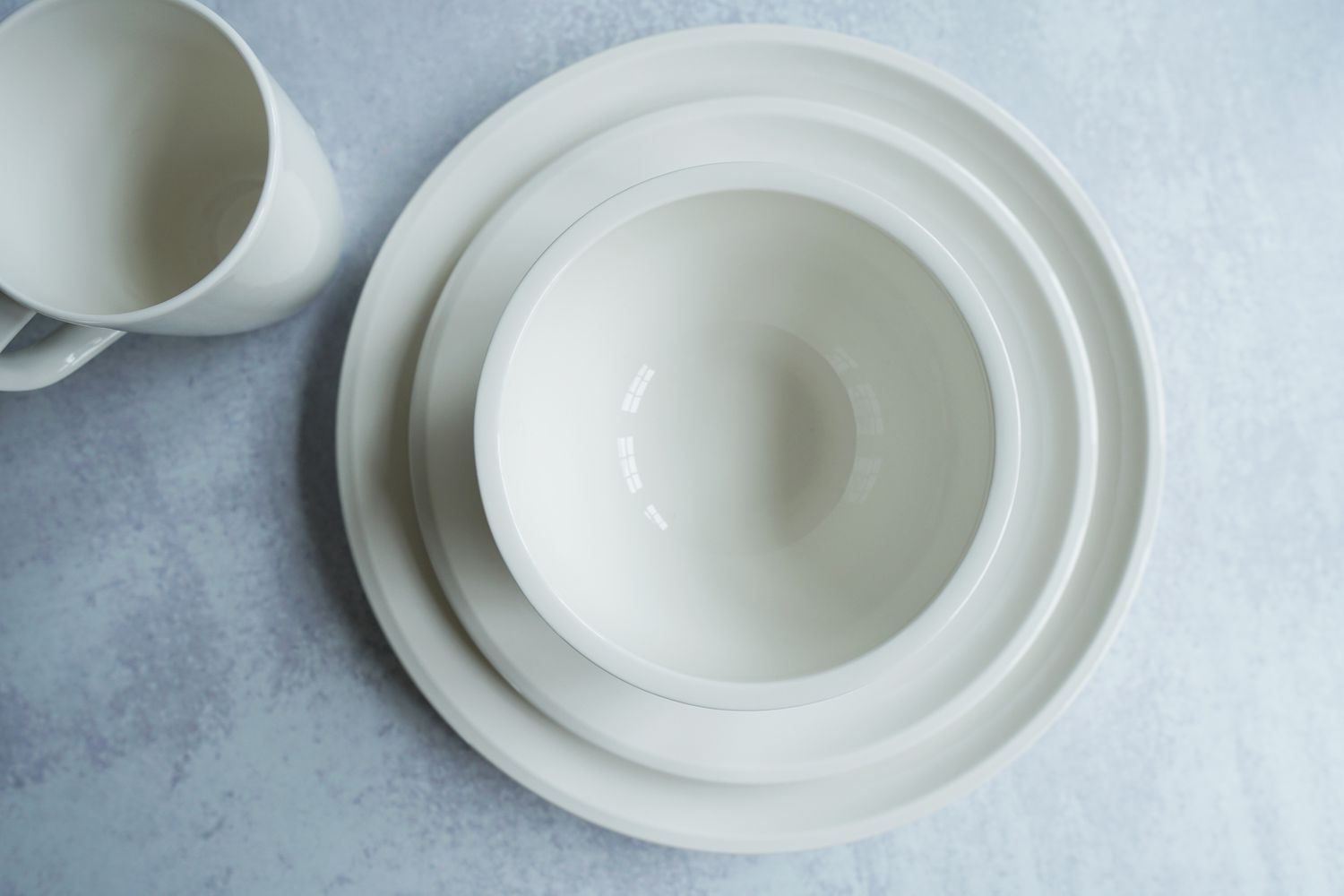 a white dinnerware set place setting on a grey surface