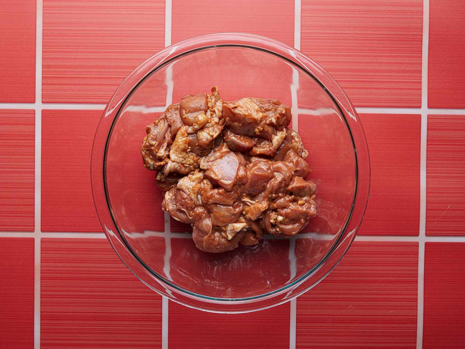 俯视红色柜台上的玻璃碗里腌制的鸡肉