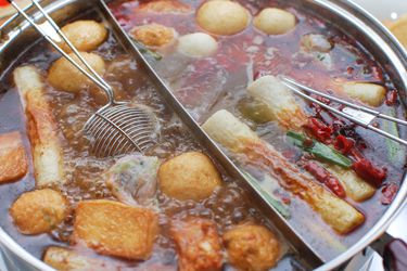 Chinese hot pot filled with simmering broth, fish balls, tofu, and vegetables