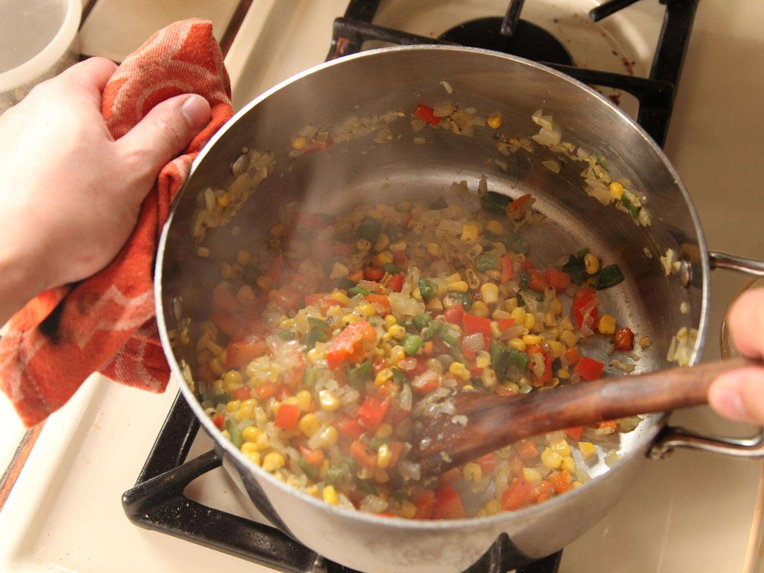 玉米粒，洋葱，柿子椒和波布拉诺辣椒sautéed在一个大炖锅里。