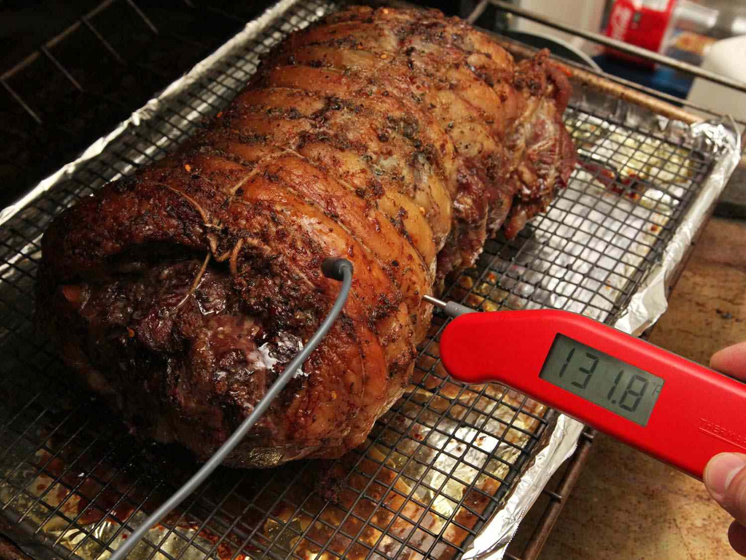 无骨羊腿:放在铁丝架上衬有锡箔的带边烤盘上的无骨、捆扎的羊腿即时读数的温度计显示华氏131.8度。