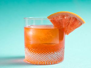 一个不寻常的内格罗尼酒,Aperol利莱酒、杜松子酒和鸡尾酒,柚子楔在玻璃的边缘。