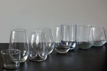 the lineup of wine glasses tested on a black countertop with white background