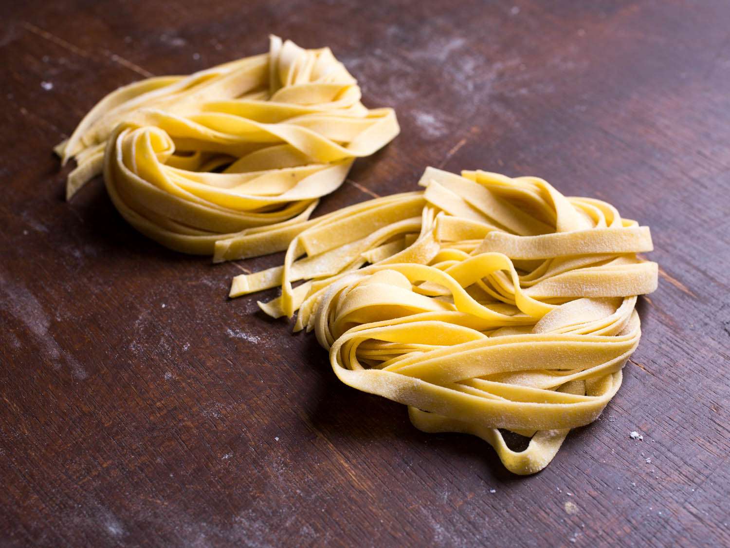 Nests of fresh pasta ribbons on a wooden surface