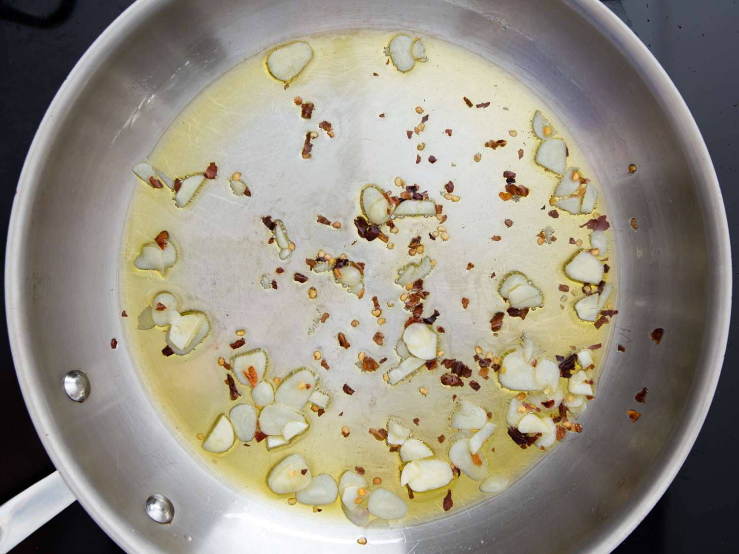将大蒜和红辣椒片切成薄片，加入橄榄油，放入不锈钢煎锅中。gydF4y2Ba