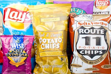An assortment of bags of salt and vinegar potato chips.