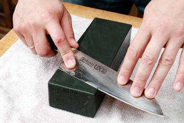 a knife being sharpened on a lower grit whetstone