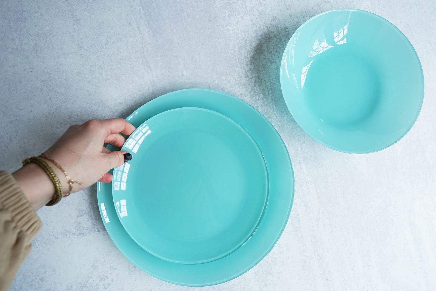 A person placing a blue plate onto another blue plate