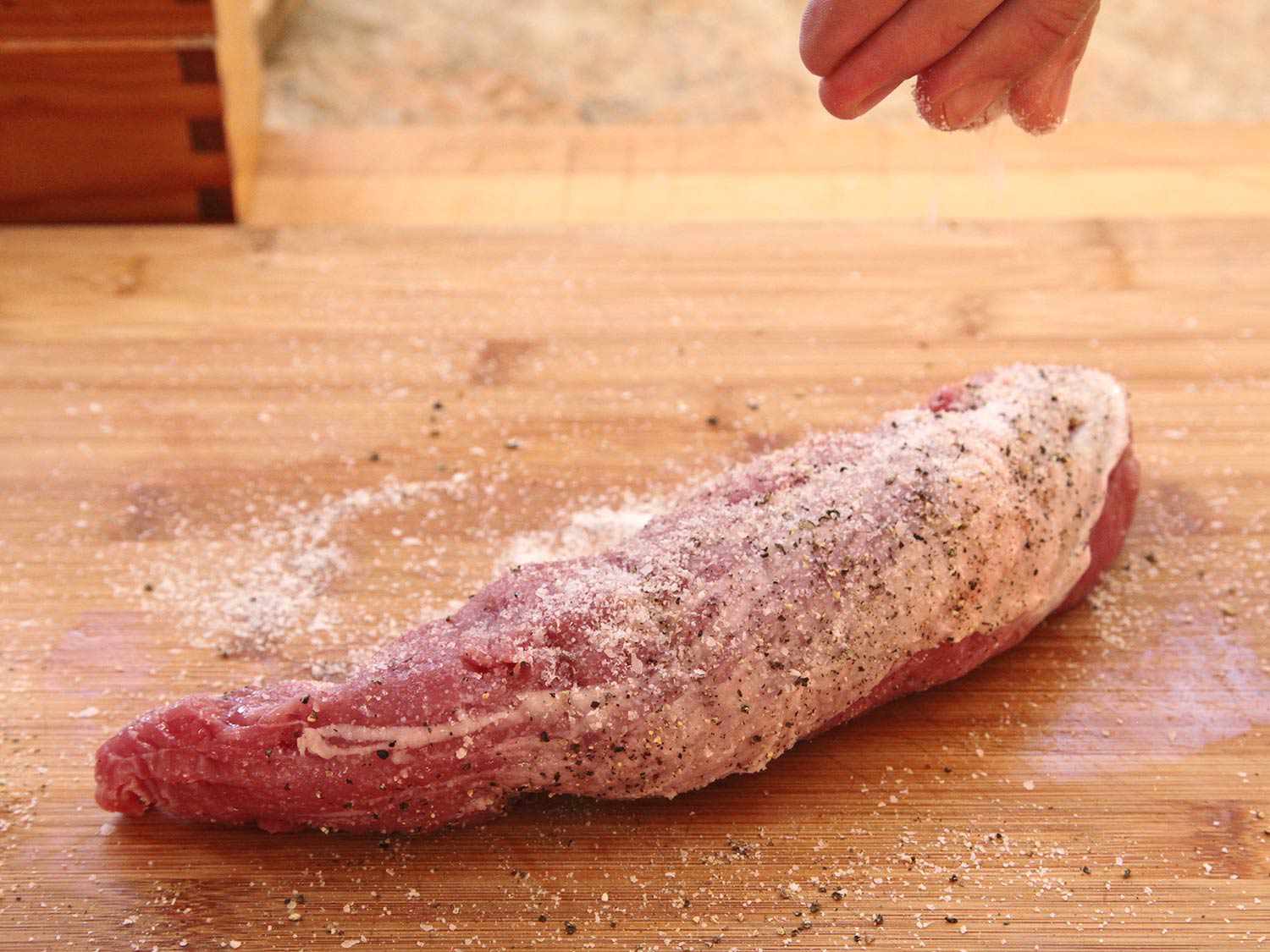 Generously seasoning a pork tenderloin with salt and pepper before cooking sous vide.