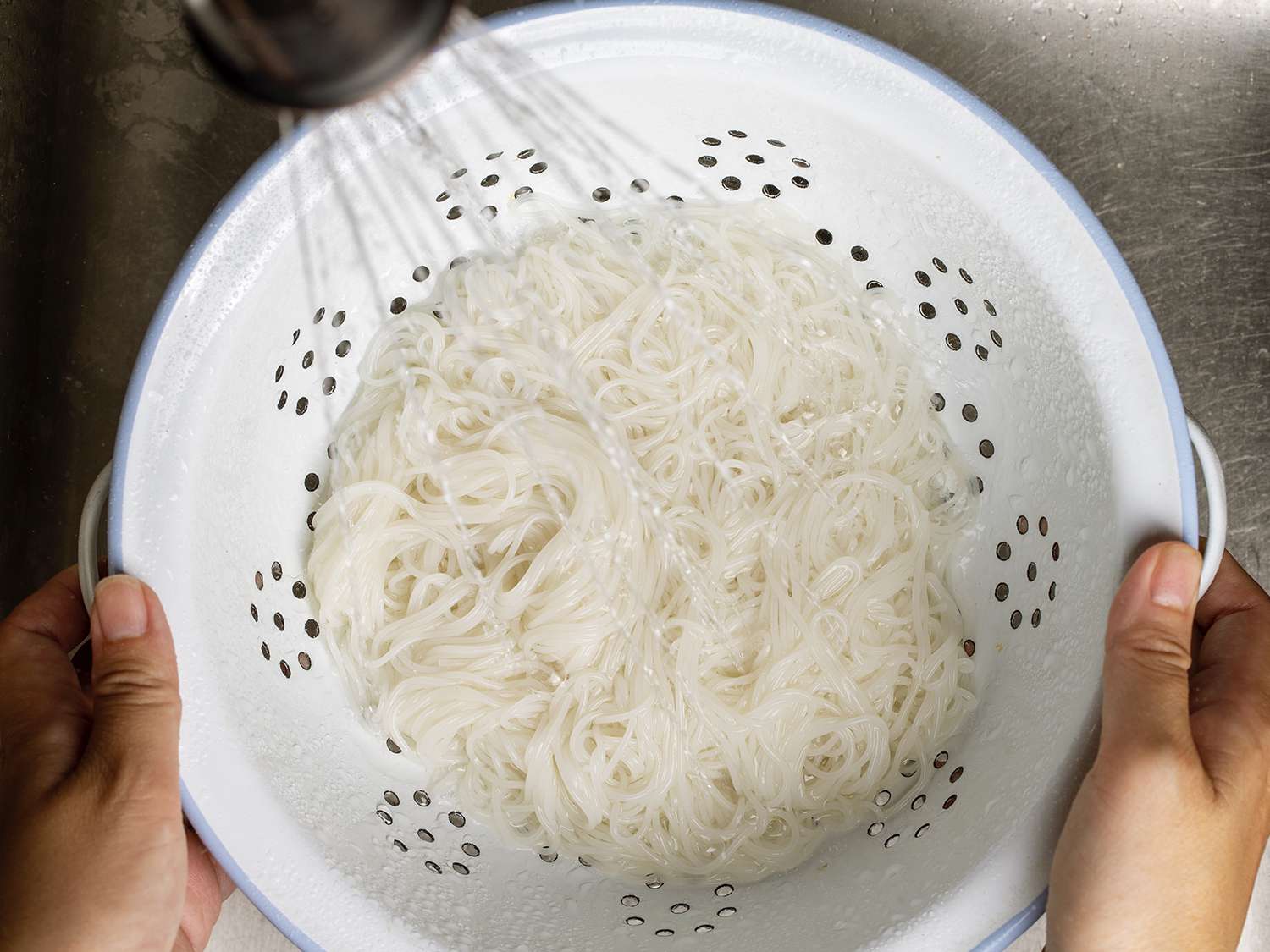 在滤锅中用水冲洗米粉。