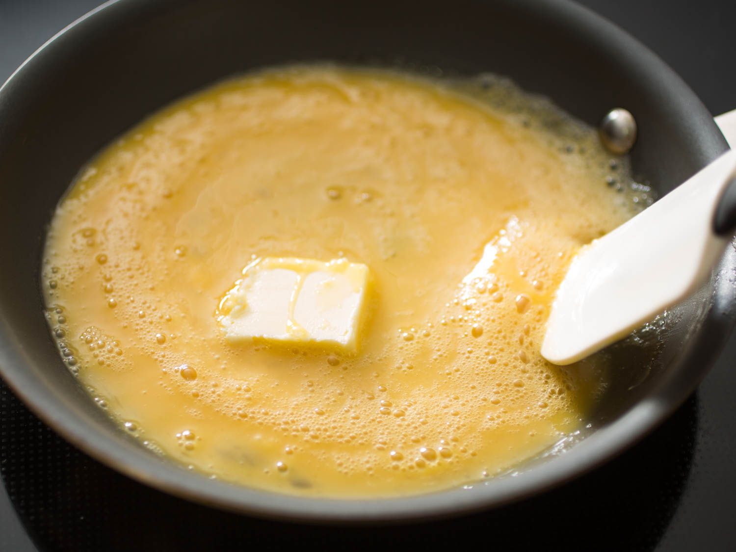 在不粘锅中加入打好的鸡蛋和黄油。