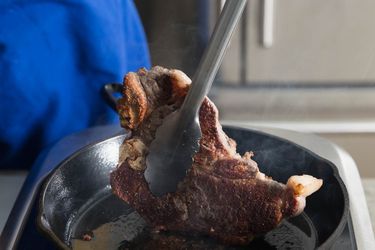 一双舌头从铸铁煎锅里叼起一块肉
