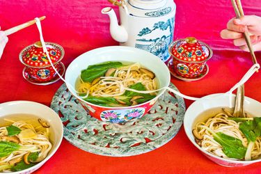 长寿一大碗面条是用一个红色的桌子,和一壶茶。食客提供自己的碗里,用筷子将长面条。