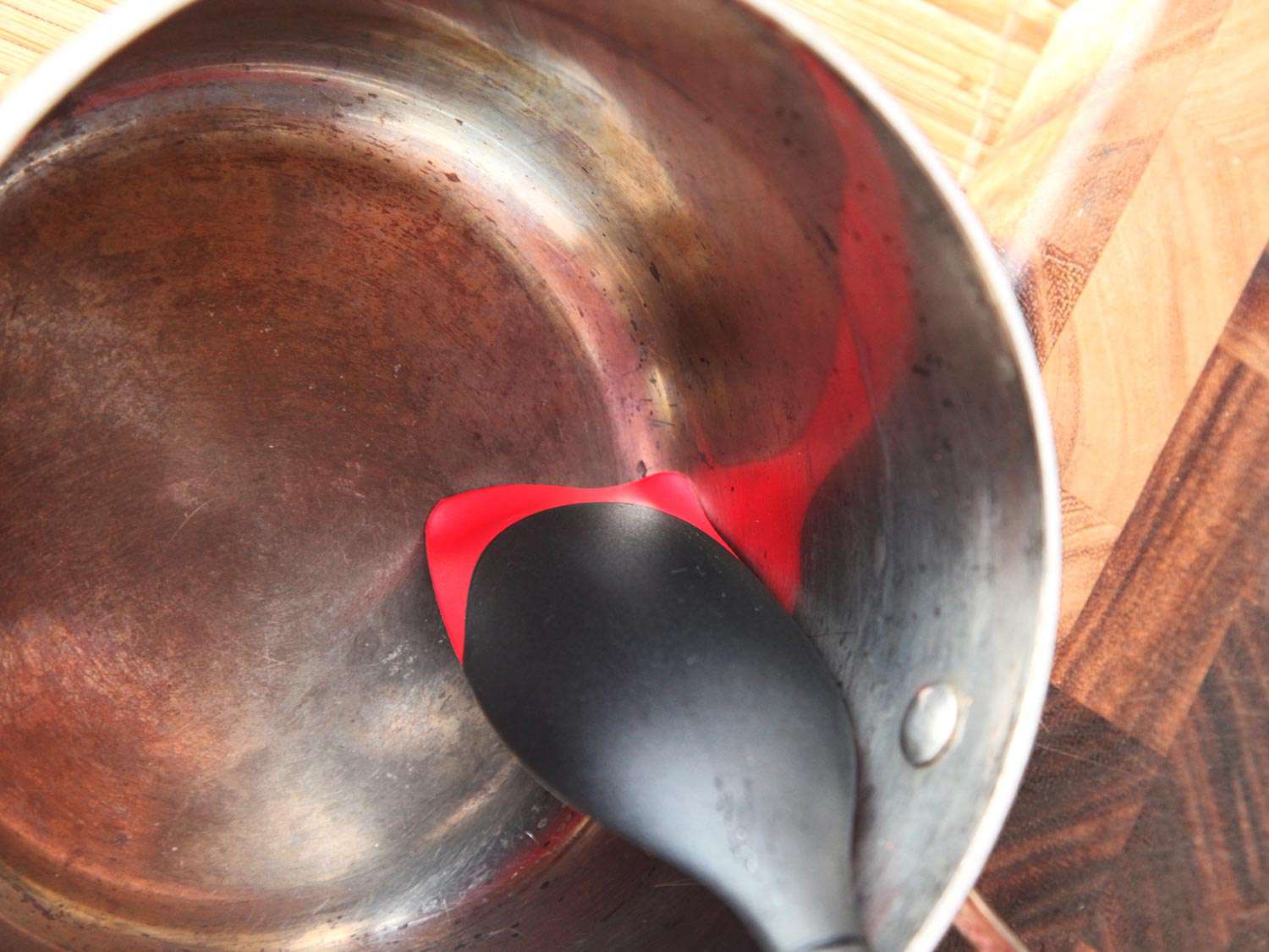 Le Creuset silicone spoon scraping corners of a pot