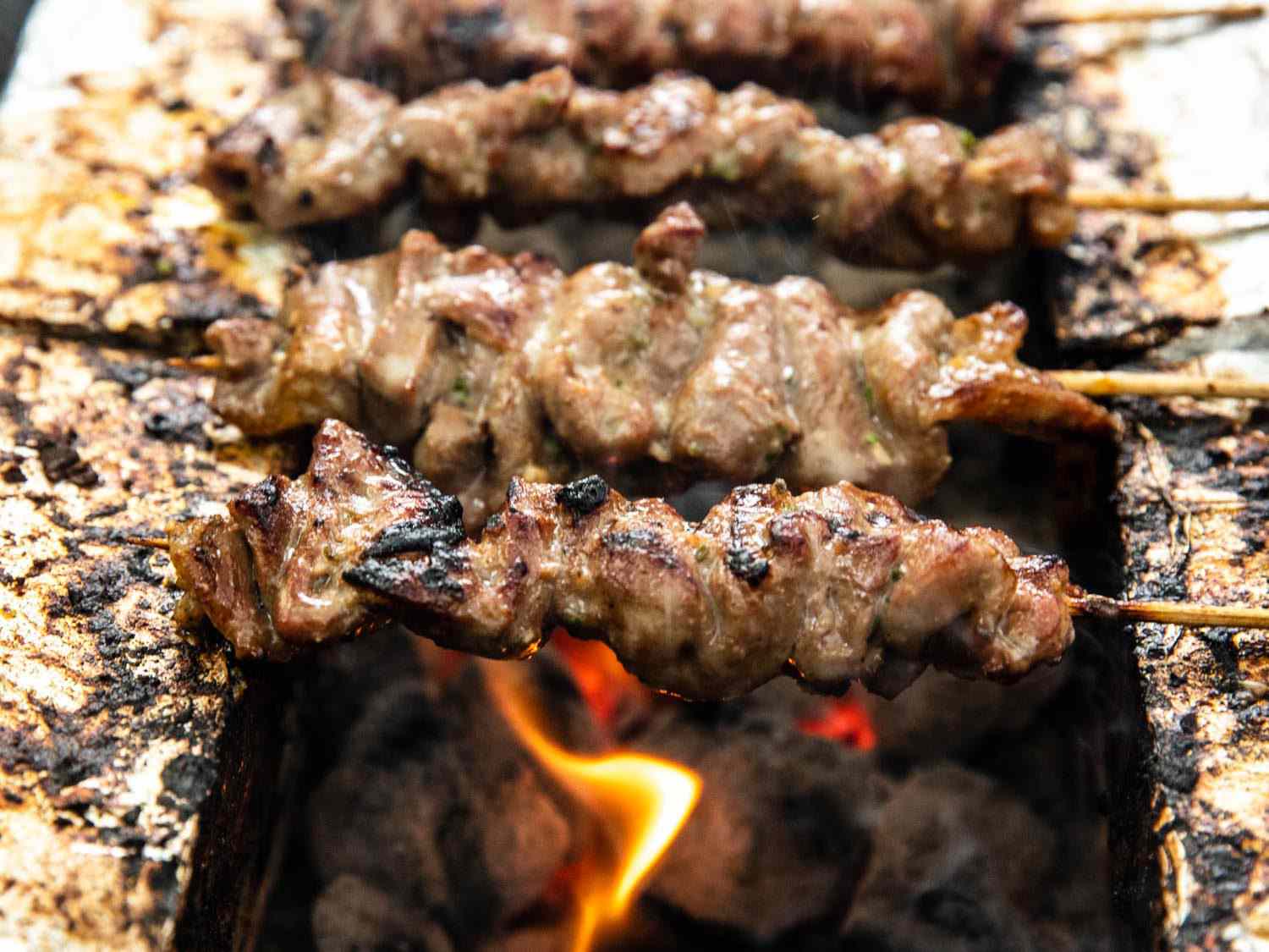 火焰在泰国猪肉串下面舔着，在煤炭上烤着