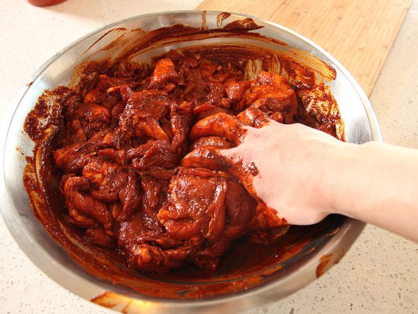 用手把红腌料和生猪肉混合在一个大银碗里，确保每一片都被盖住。