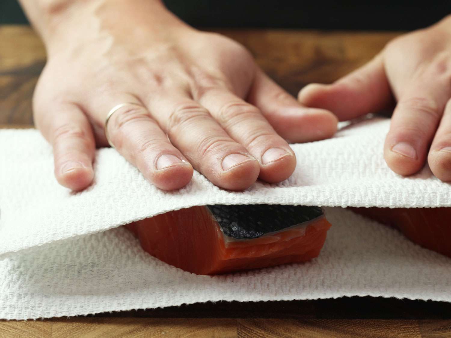 用纸巾将带皮的生三文鱼片拍干。