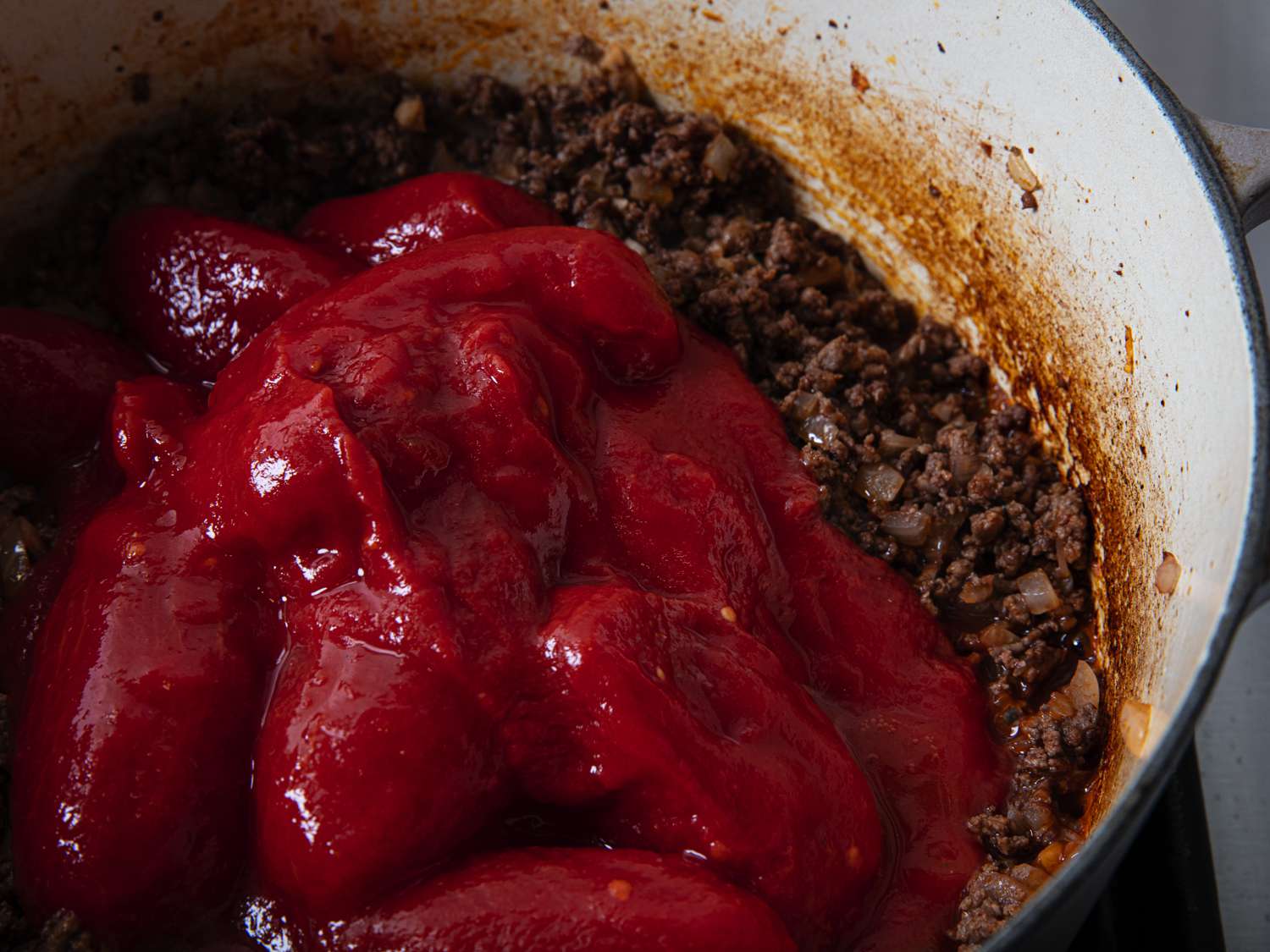 俯视图罐头番茄添加到肉在锅