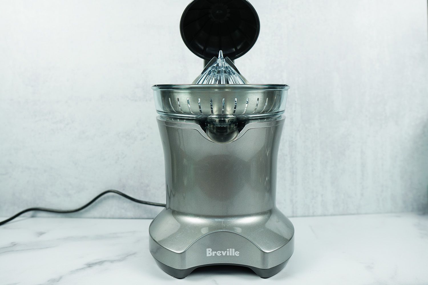 a front-on shot of a Breville electric citrus juicer against a grey background