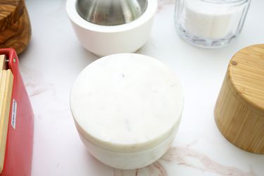 a marble salt cellar surrounded by other salt cellars on a pink and white marble countertop