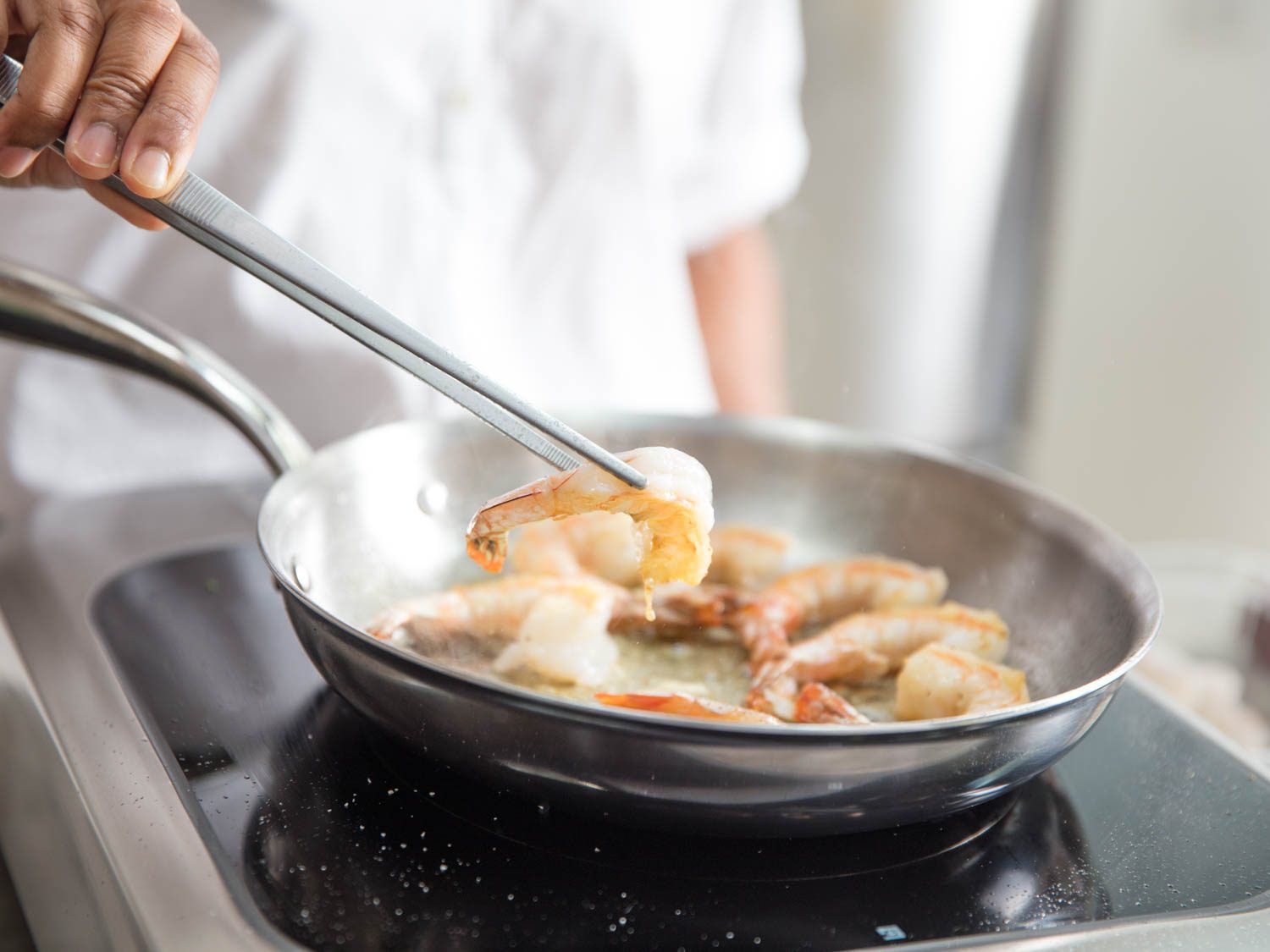 举起一只虾的厨房锅使用镊子