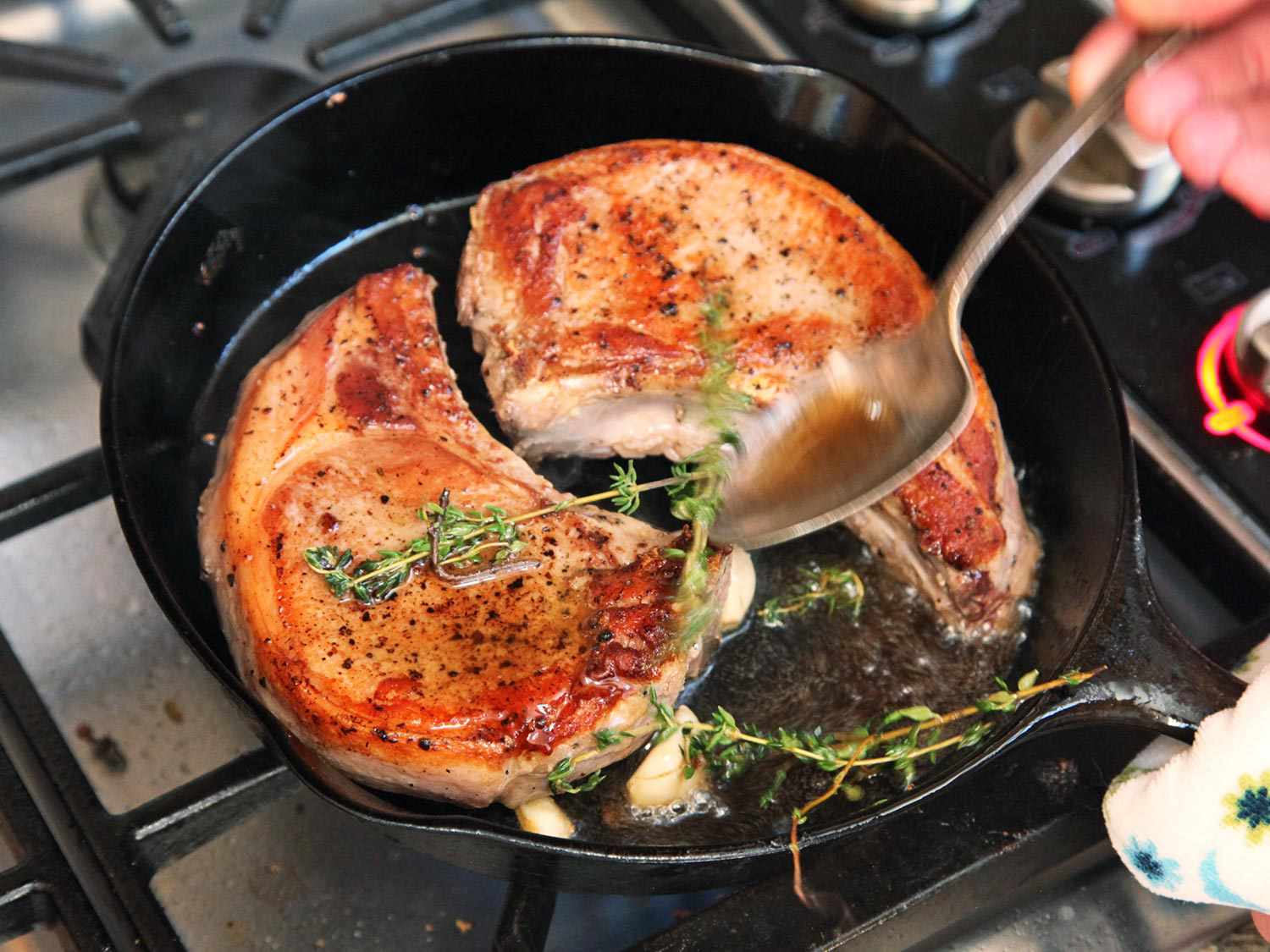 Basting sous vide pork chops in a cast iron skillet with butter, garlic, and thyme.