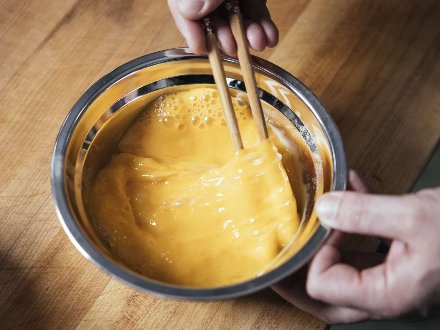 用筷子把玉米淀粉和鸡蛋放在一个金属碗里搅拌均匀。