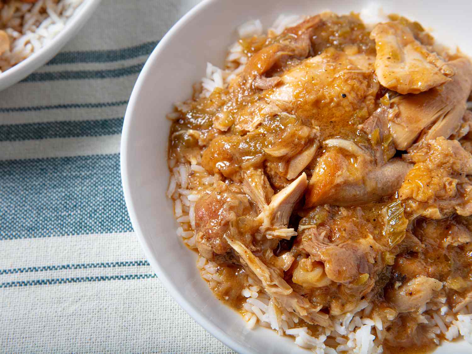 近距离的形象lowcounty炖鸡在米饭。里面的食物是白色的陶瓷碗,放在变形和染色抹布。