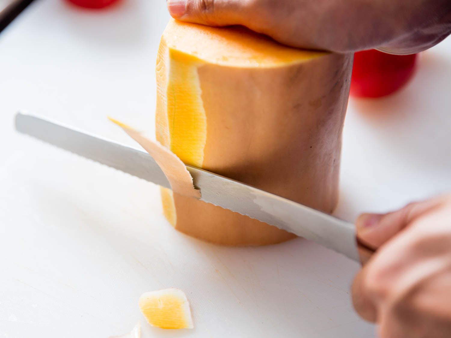 a bread knife peeling a butternut squash
