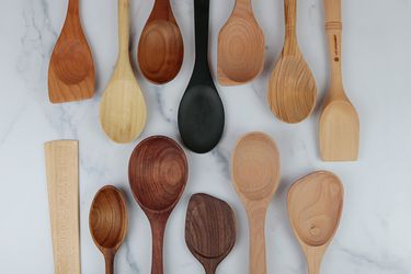 a collection of different wooden spoons rest next to each other on a white marble background